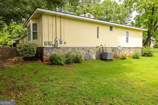 view of side of home featuring cooling unit and a lawn