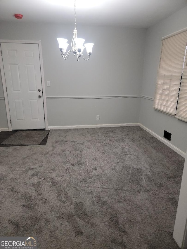 carpeted spare room with a notable chandelier