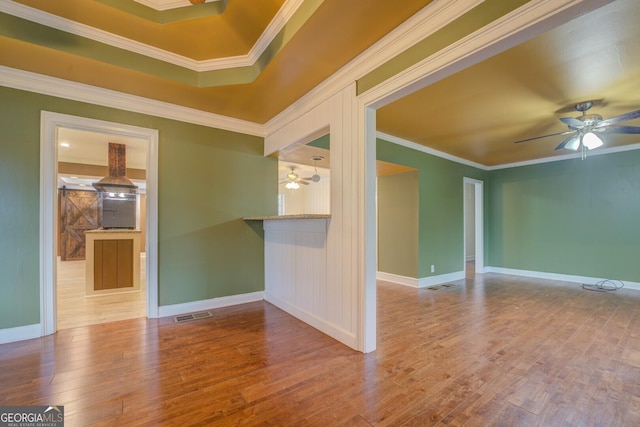 spare room with visible vents, baseboards, ceiling fan, ornamental molding, and light wood-type flooring