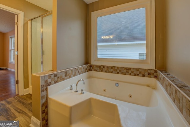 bathroom featuring an enclosed shower, a tub with jets, and wood finished floors