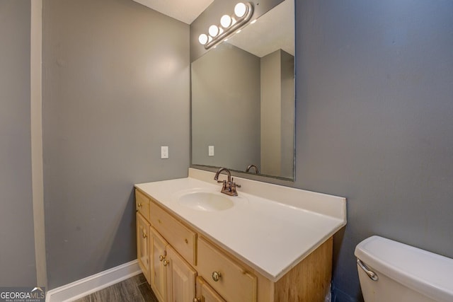 bathroom featuring baseboards, vanity, toilet, and wood finished floors