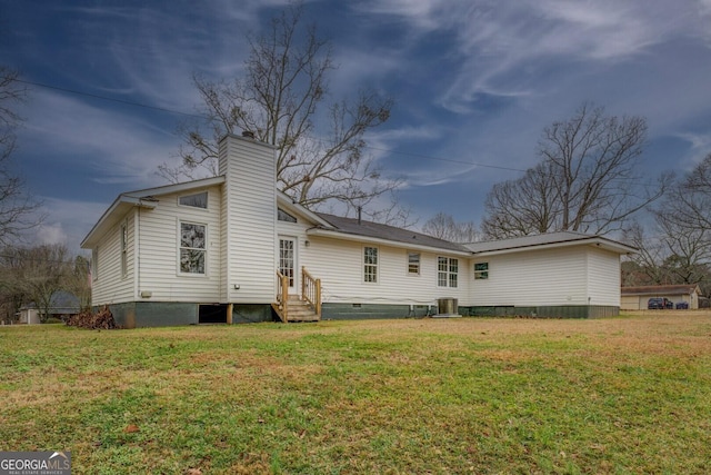 back of property with entry steps, a yard, central AC unit, and a chimney