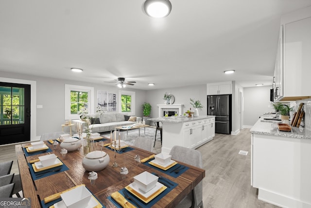 dining space with ceiling fan and light wood-type flooring