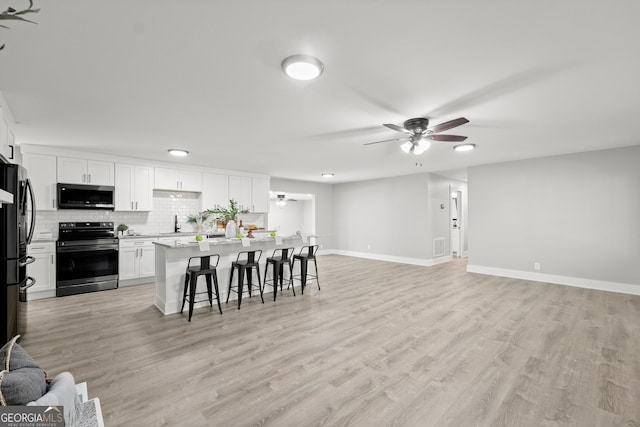 kitchen featuring a center island, a breakfast bar area, ceiling fan, white cabinetry, and stainless steel appliances