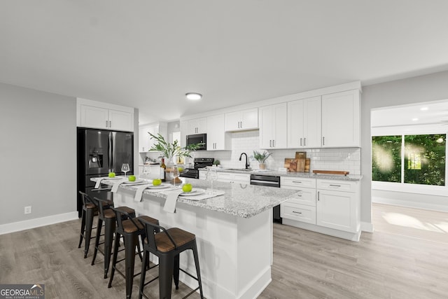 kitchen with backsplash, sink, appliances with stainless steel finishes, a kitchen bar, and white cabinetry