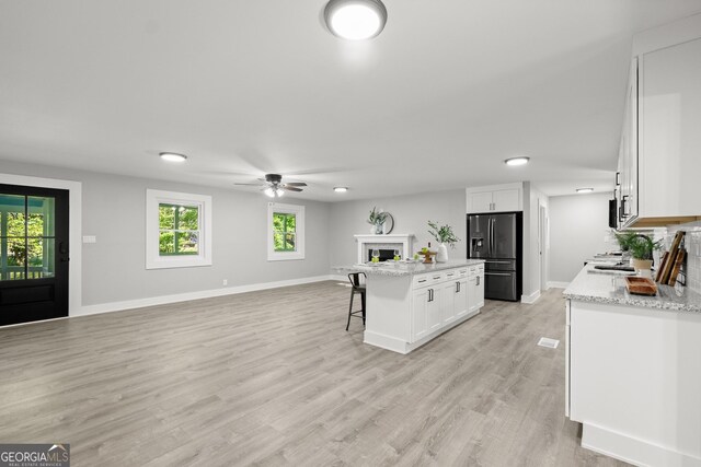 kitchen with a kitchen bar, fridge with ice dispenser, white cabinetry, and a center island