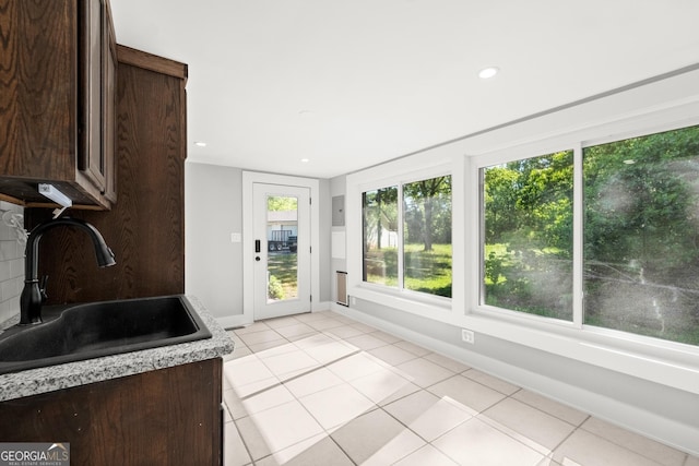 kitchen featuring dark brown cabinets, light tile patterned floors, and sink