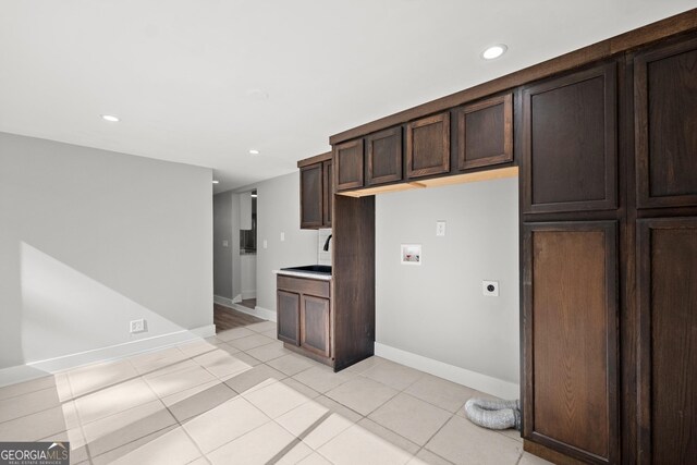 kitchen with dark brown cabinets, light tile patterned floors, and sink