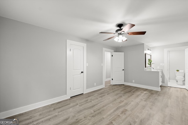 unfurnished bedroom featuring connected bathroom, light hardwood / wood-style floors, and ceiling fan