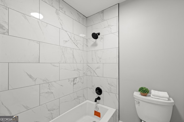 bathroom with toilet and tiled shower / bath