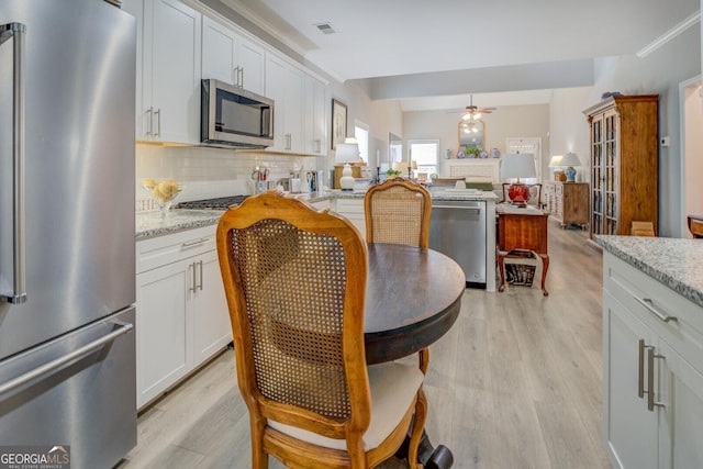 kitchen with stainless steel appliances, visible vents, decorative backsplash, ceiling fan, and light wood-type flooring