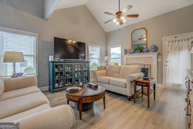 living room with high vaulted ceiling, a fireplace, a wealth of natural light, and light wood-style floors