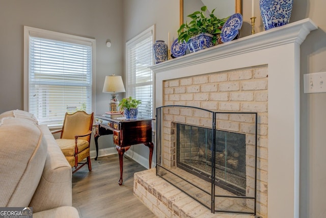 living area with a brick fireplace, baseboards, and wood finished floors