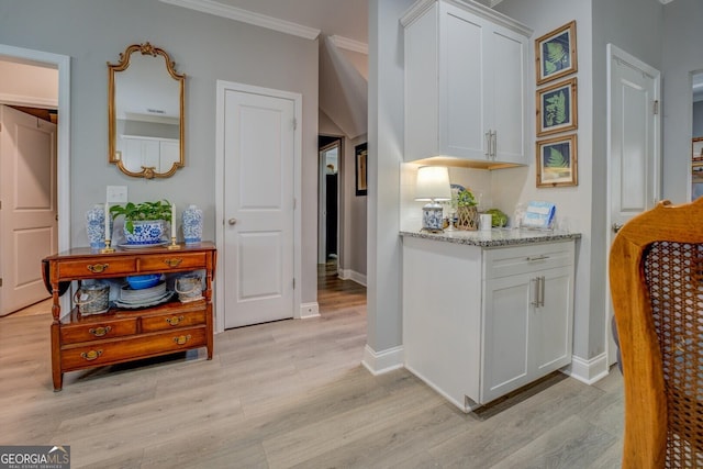 interior space featuring light wood-style floors, baseboards, and ornamental molding