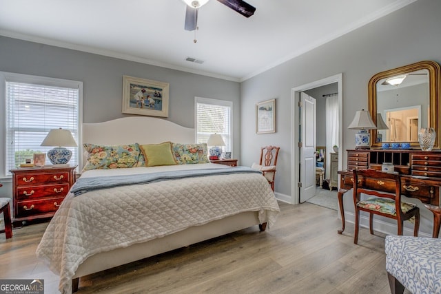 bedroom with ceiling fan, wood finished floors, visible vents, baseboards, and crown molding