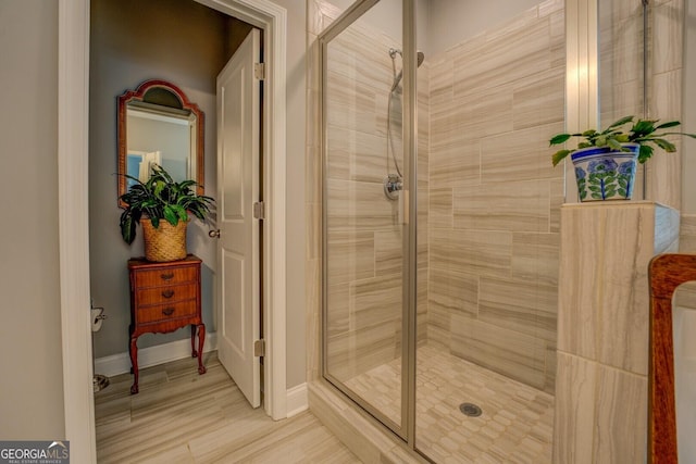 full bath with a shower stall, baseboards, and wood finished floors