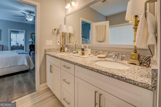 bathroom featuring ensuite bathroom, wood finished floors, a sink, visible vents, and double vanity