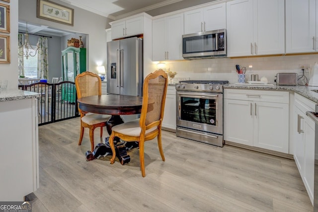 kitchen featuring light wood-style flooring, white cabinetry, appliances with stainless steel finishes, decorative backsplash, and crown molding