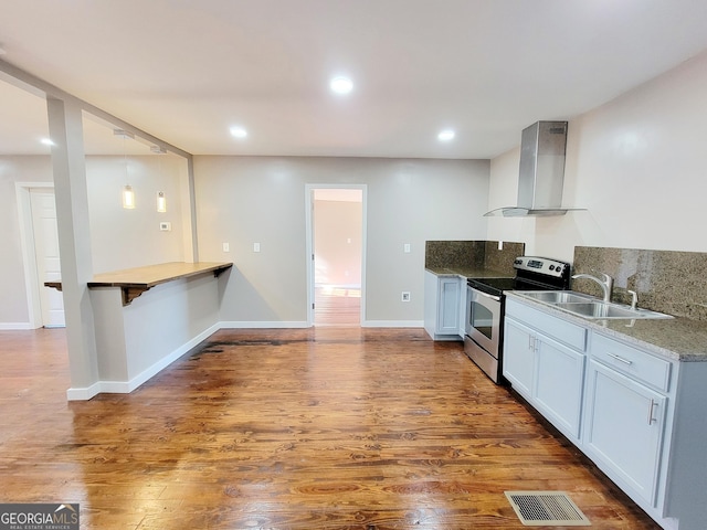 kitchen featuring sink, hanging light fixtures, electric range, wall chimney exhaust hood, and decorative backsplash