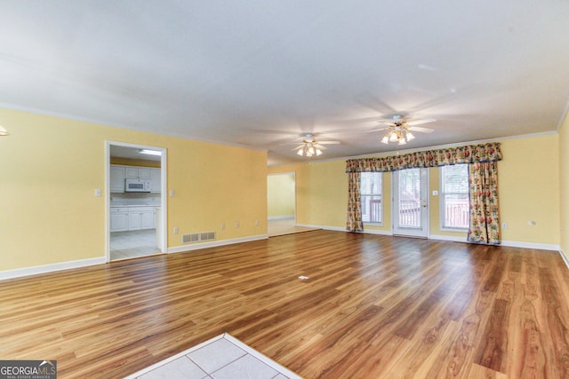 unfurnished living room featuring ceiling fan, wood-type flooring, and crown molding