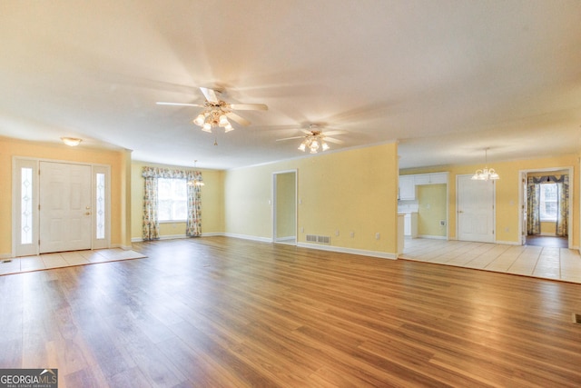 unfurnished living room featuring light hardwood / wood-style floors and ceiling fan with notable chandelier