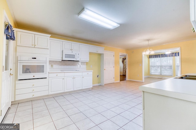 kitchen with white appliances, backsplash, decorative light fixtures, a notable chandelier, and white cabinetry