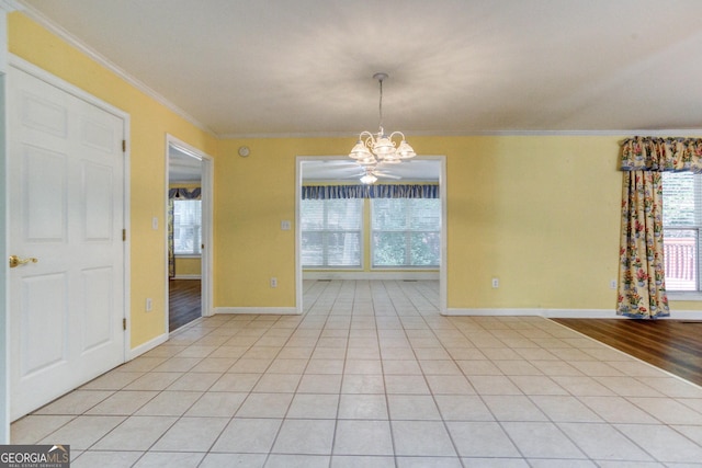 tiled empty room featuring ceiling fan with notable chandelier and crown molding