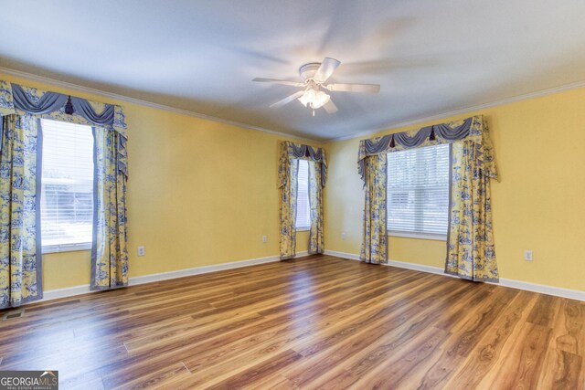 unfurnished room featuring plenty of natural light, wood-type flooring, and ornamental molding