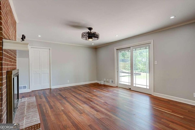 unfurnished living room featuring crown molding, dark hardwood / wood-style flooring, and a brick fireplace