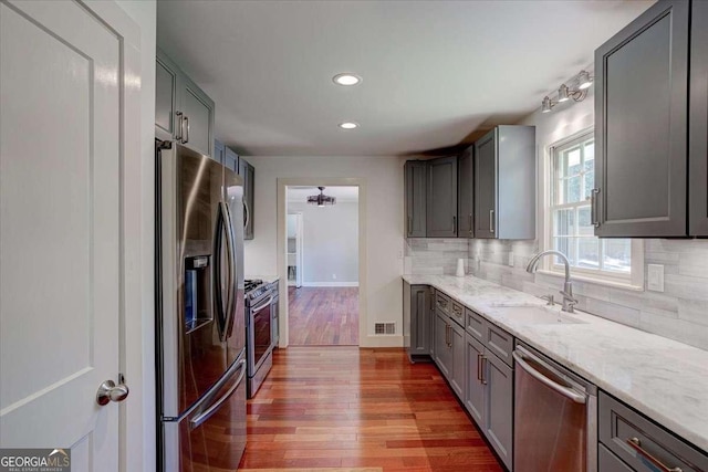 kitchen with decorative backsplash, sink, light hardwood / wood-style flooring, and appliances with stainless steel finishes