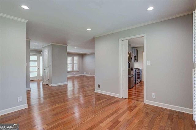 empty room with ornamental molding and light hardwood / wood-style flooring