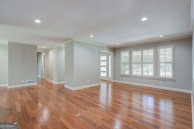 spare room featuring light wood-type flooring and crown molding