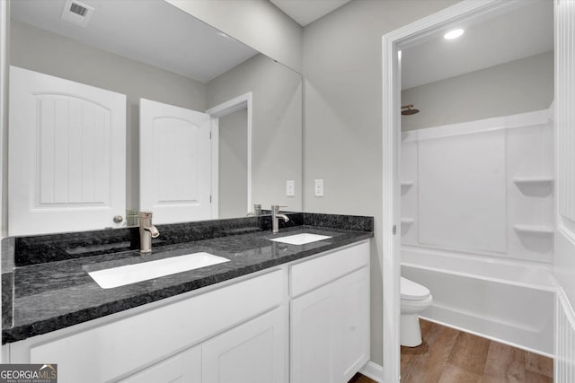 full bathroom featuring hardwood / wood-style flooring, vanity, toilet, and shower / washtub combination