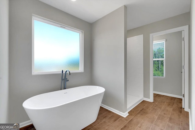 bathroom with hardwood / wood-style floors, independent shower and bath, and a healthy amount of sunlight