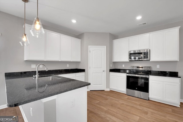 kitchen with white cabinets, sink, appliances with stainless steel finishes, decorative light fixtures, and kitchen peninsula