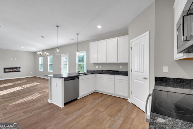 kitchen with white cabinetry, kitchen peninsula, stainless steel appliances, and hanging light fixtures