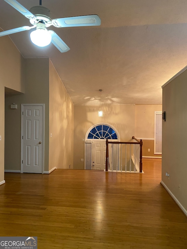 interior space with ceiling fan, hardwood / wood-style flooring, and high vaulted ceiling