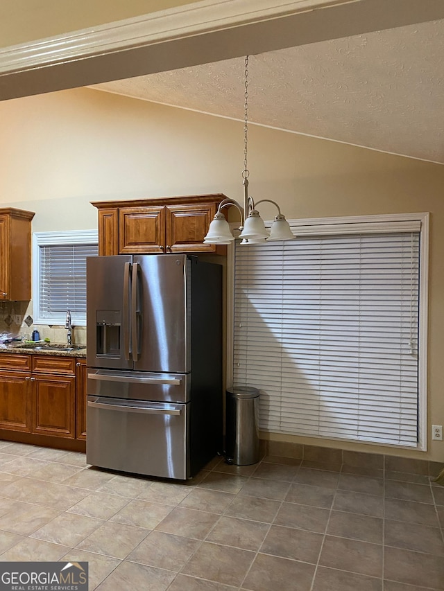 kitchen featuring lofted ceiling, stainless steel refrigerator with ice dispenser, sink, an inviting chandelier, and a textured ceiling