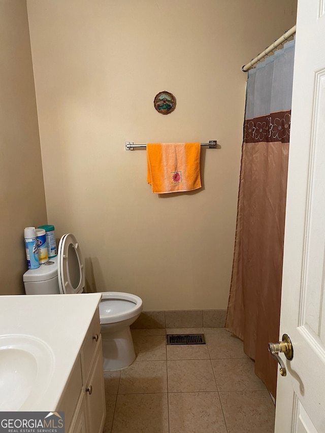 bathroom with toilet, vanity, and tile patterned flooring