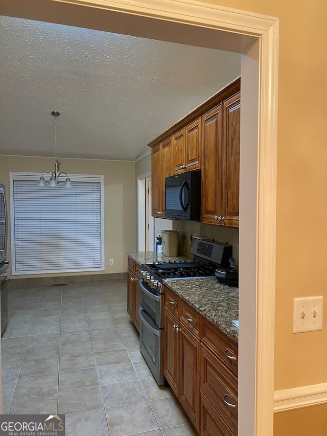 kitchen featuring an inviting chandelier, decorative light fixtures, range with two ovens, dark stone counters, and a textured ceiling