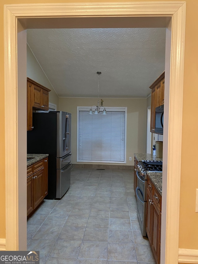 kitchen with vaulted ceiling, appliances with stainless steel finishes, stone counters, and a chandelier