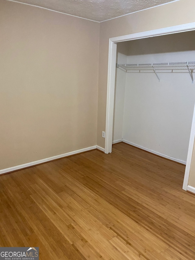 unfurnished bedroom with a closet, a textured ceiling, and light hardwood / wood-style flooring