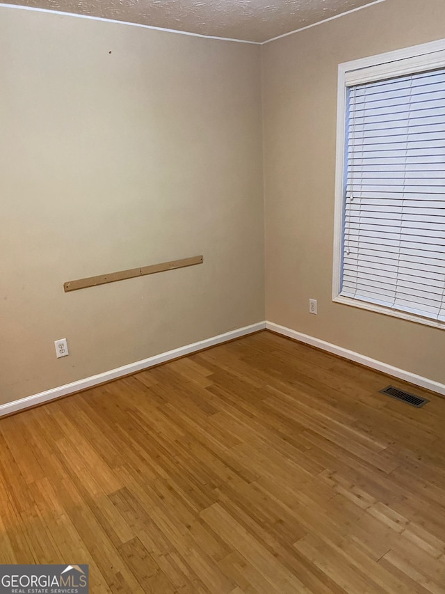 empty room with a textured ceiling and hardwood / wood-style floors