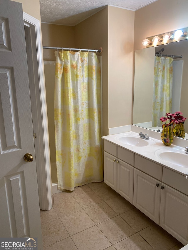 bathroom with a textured ceiling, tile patterned flooring, walk in shower, and vanity