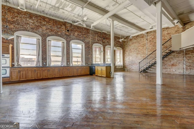 unfurnished room featuring sink, a high ceiling, brick wall, and dark wood-type flooring