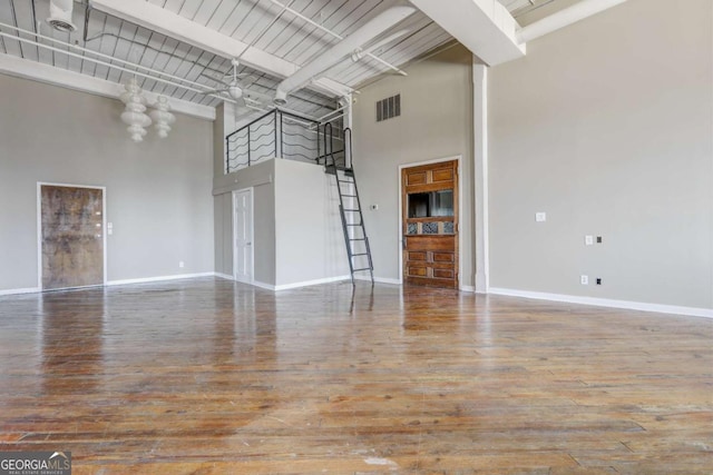 unfurnished living room featuring hardwood / wood-style floors, beam ceiling, and a high ceiling