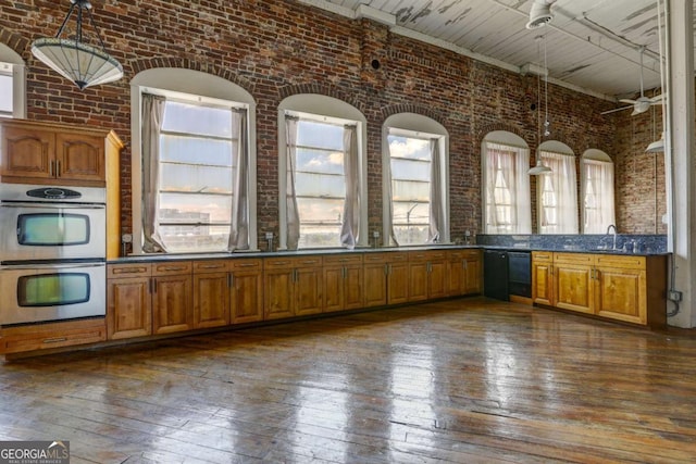 kitchen with sink, stainless steel double oven, a healthy amount of sunlight, and brick wall