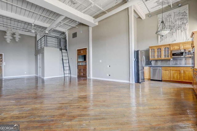 unfurnished living room with beam ceiling, wood-type flooring, and a towering ceiling