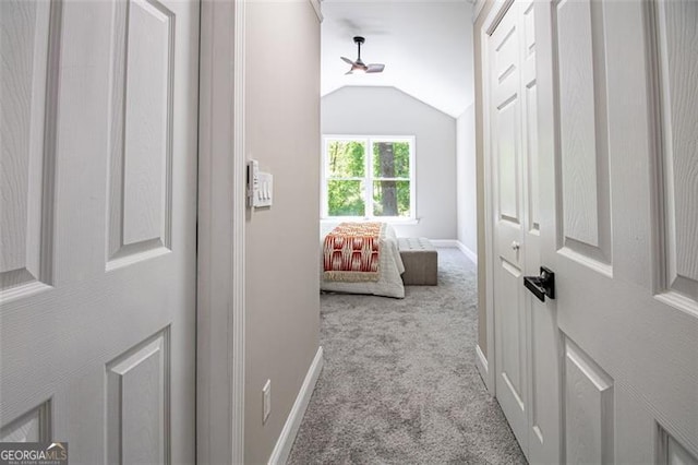 corridor featuring light carpet and vaulted ceiling