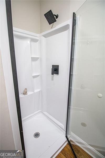 bathroom with wood-type flooring and walk in shower